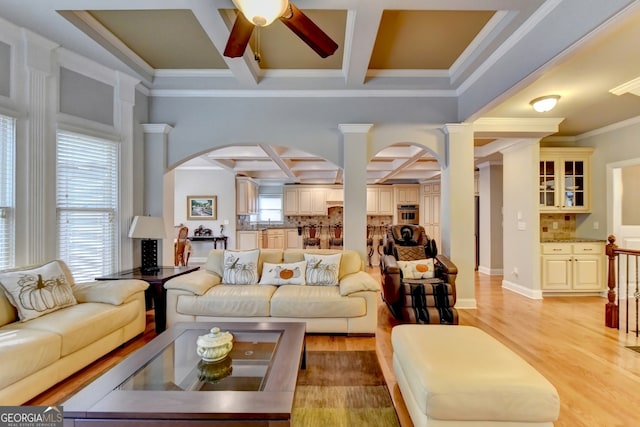 living room with crown molding, coffered ceiling, beamed ceiling, ceiling fan, and light hardwood / wood-style flooring