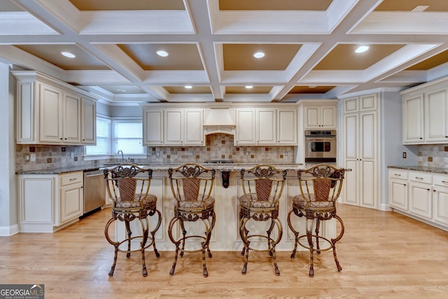 kitchen featuring appliances with stainless steel finishes, light hardwood / wood-style floors, a kitchen island, and light stone countertops