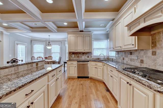 kitchen featuring decorative light fixtures, cream cabinets, light stone counters, and stainless steel appliances