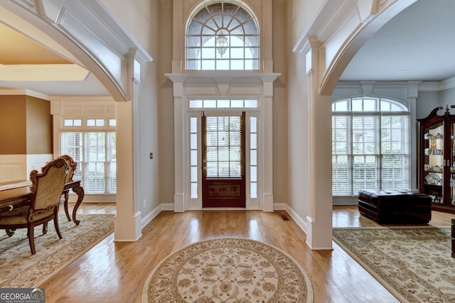 foyer entrance featuring light hardwood / wood-style flooring, a healthy amount of sunlight, and crown molding