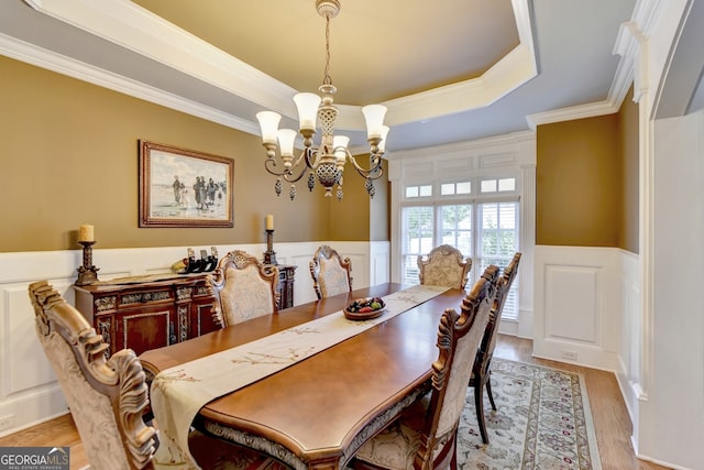 dining room featuring ornamental molding, an inviting chandelier, light hardwood / wood-style floors, and a raised ceiling