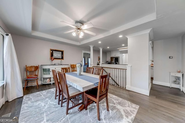 dining area featuring a tray ceiling, ceiling fan, and hardwood / wood-style flooring