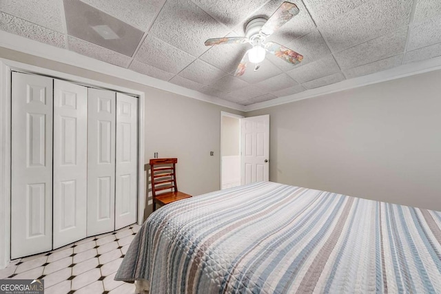 bedroom with a paneled ceiling, a closet, and ceiling fan