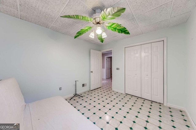 bedroom featuring a paneled ceiling, ceiling fan, and a closet