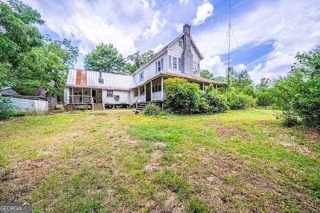 back of house featuring metal roof, a lawn, and a chimney