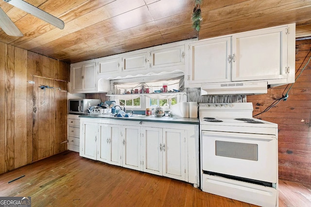 kitchen featuring stainless steel microwave, extractor fan, wood walls, and white range with electric cooktop