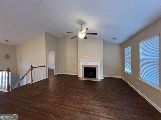 unfurnished living room featuring ceiling fan, a textured ceiling, and dark hardwood / wood-style floors