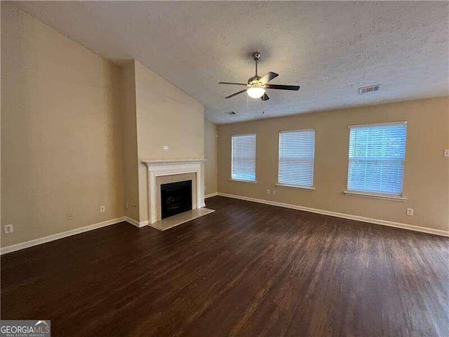 unfurnished living room with ceiling fan, a textured ceiling, and dark hardwood / wood-style flooring