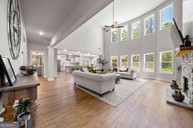 living room featuring a fireplace, light wood-type flooring, ceiling fan, and plenty of natural light