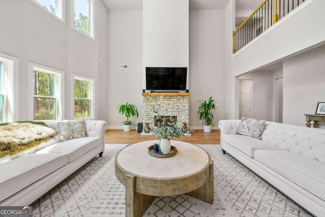 living room with a high ceiling, hardwood / wood-style floors, and a healthy amount of sunlight