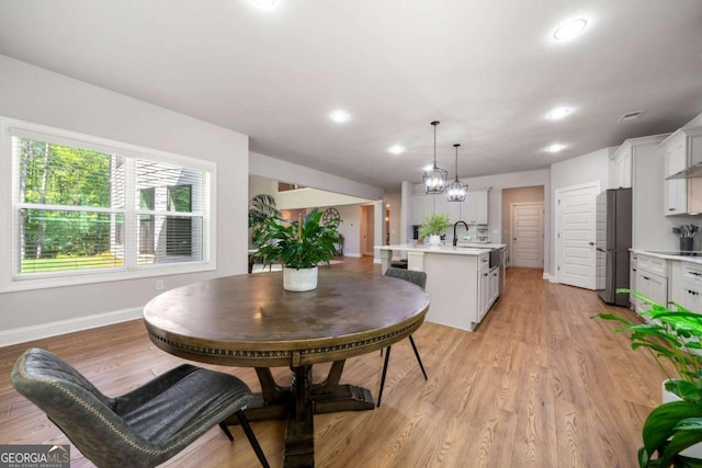 dining space with light wood-type flooring, sink, and an inviting chandelier