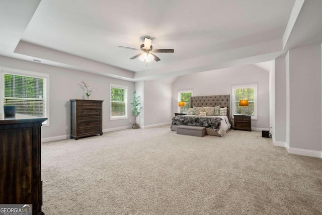 carpeted bedroom with ceiling fan and a raised ceiling