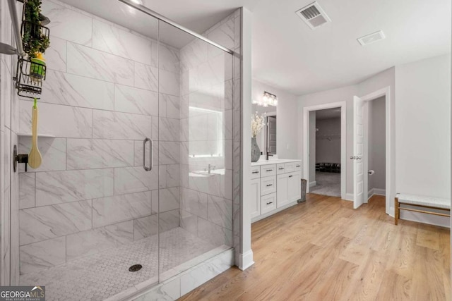 bathroom featuring walk in shower, wood-type flooring, and vanity