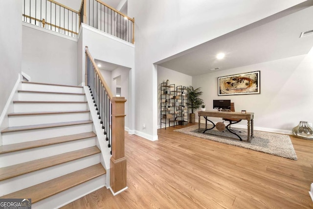 staircase with hardwood / wood-style flooring and a high ceiling