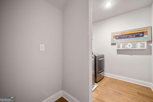 clothes washing area with washer and clothes dryer and wood-type flooring