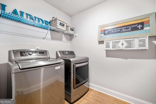 clothes washing area with washing machine and clothes dryer and hardwood / wood-style flooring