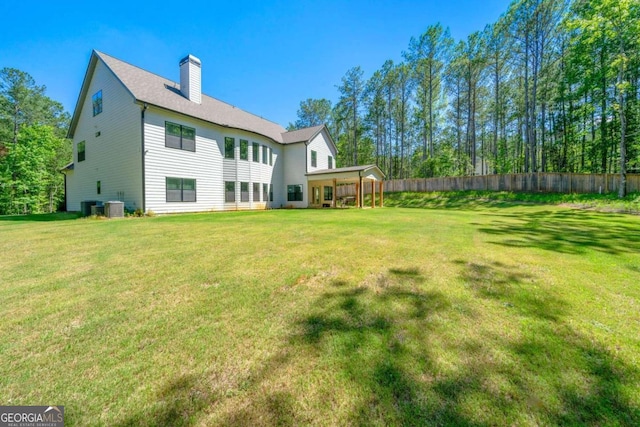 rear view of house with a lawn and central AC