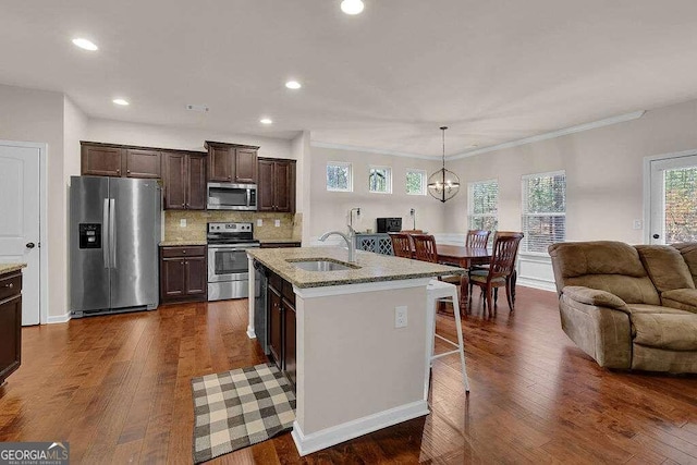 kitchen with stainless steel appliances, dark hardwood / wood-style floors, sink, and a kitchen island with sink