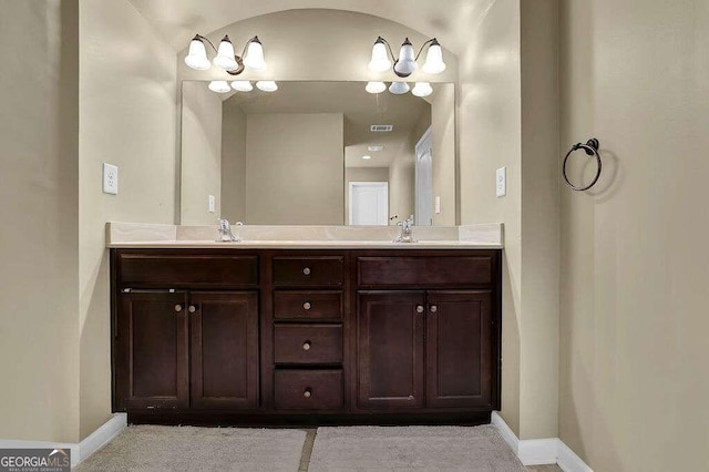 bathroom featuring double vanity, a sink, visible vents, and baseboards