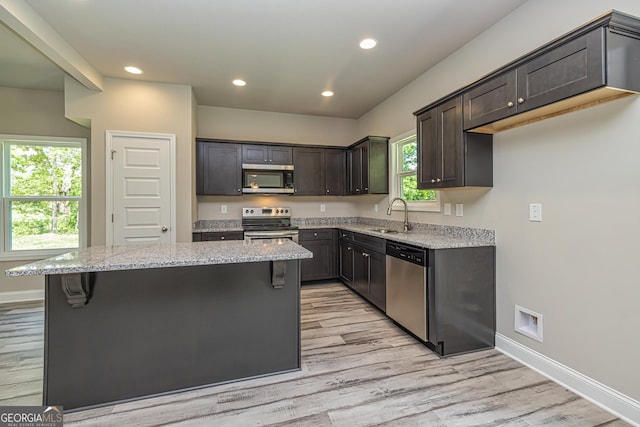 kitchen featuring stainless steel appliances, sink, a kitchen island, and a wealth of natural light