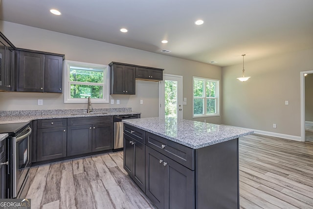 kitchen featuring a kitchen island, pendant lighting, sink, stainless steel appliances, and light wood-type flooring