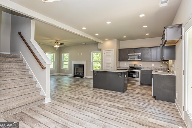 kitchen featuring sink, a center island, ceiling fan, stainless steel appliances, and light hardwood / wood-style flooring