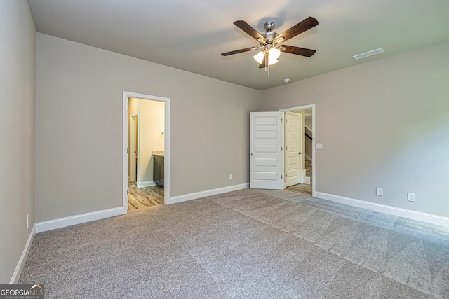 unfurnished bedroom with connected bathroom, light colored carpet, and ceiling fan