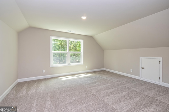 bonus room featuring vaulted ceiling and light colored carpet