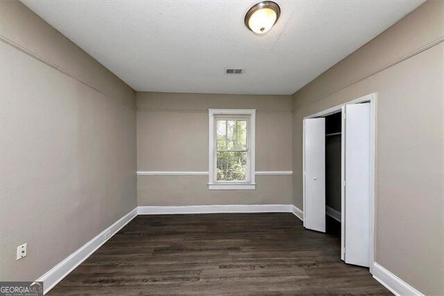 unfurnished bedroom featuring a closet and dark hardwood / wood-style floors