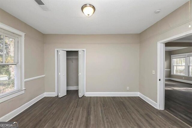 unfurnished bedroom with dark hardwood / wood-style flooring and a closet