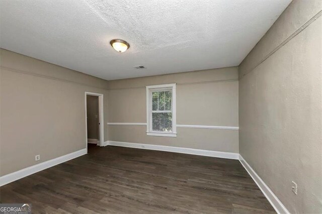 unfurnished room featuring a textured ceiling and dark hardwood / wood-style flooring