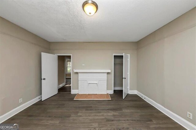 unfurnished living room with a textured ceiling and dark hardwood / wood-style flooring