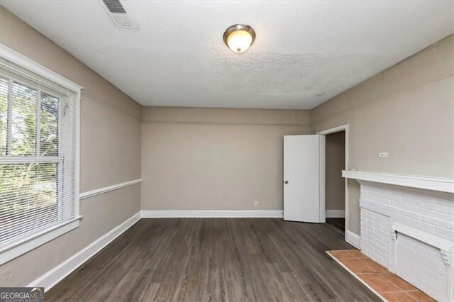 unfurnished living room featuring a textured ceiling and dark hardwood / wood-style flooring