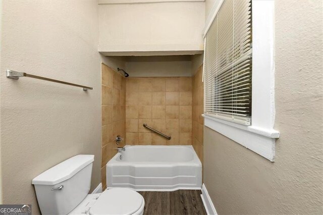 bathroom with tiled shower / bath, hardwood / wood-style flooring, and toilet