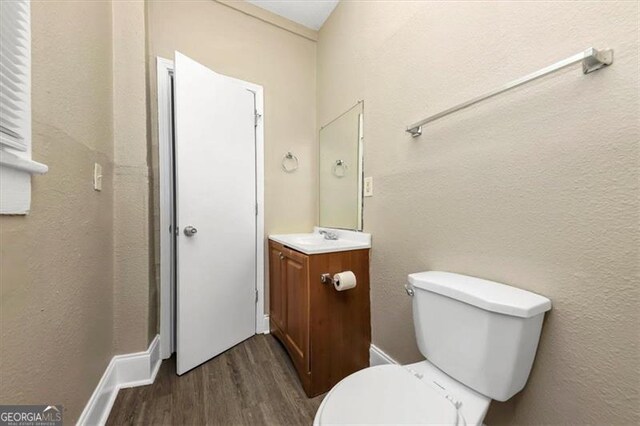 bathroom with toilet, vanity, and hardwood / wood-style flooring