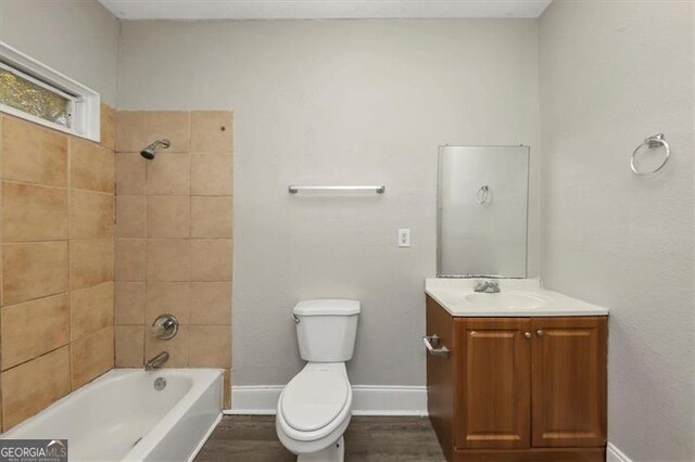 full bathroom with hardwood / wood-style floors, vanity, toilet, and tiled shower / bath