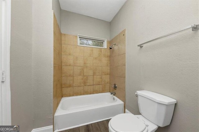 bathroom with toilet, tiled shower / bath, and hardwood / wood-style floors