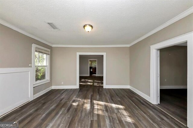 unfurnished room featuring a textured ceiling, dark hardwood / wood-style floors, and crown molding