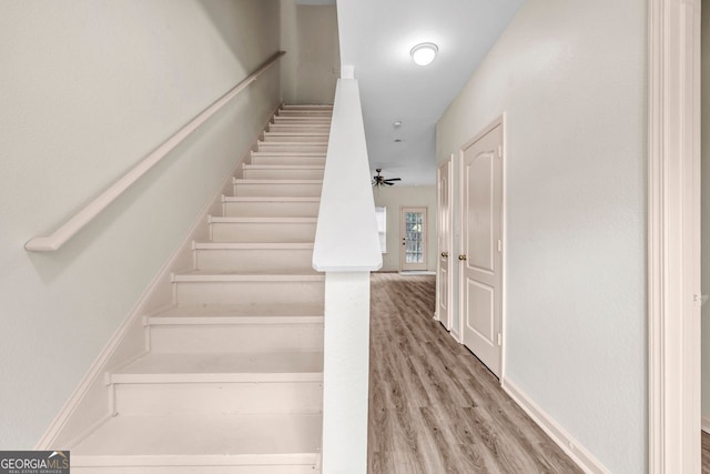 stairs with hardwood / wood-style floors and ceiling fan