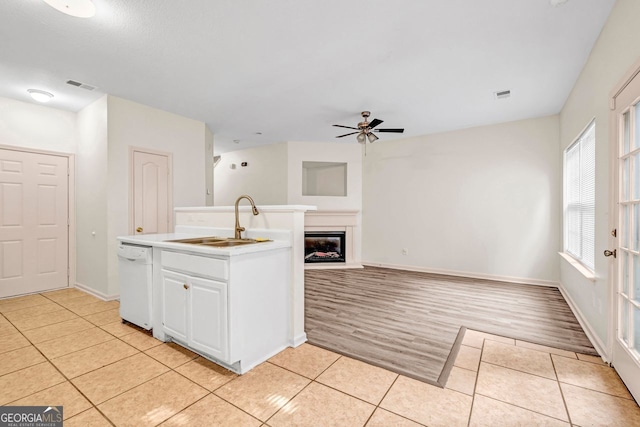 kitchen with light hardwood / wood-style floors, sink, ceiling fan, white cabinets, and dishwasher