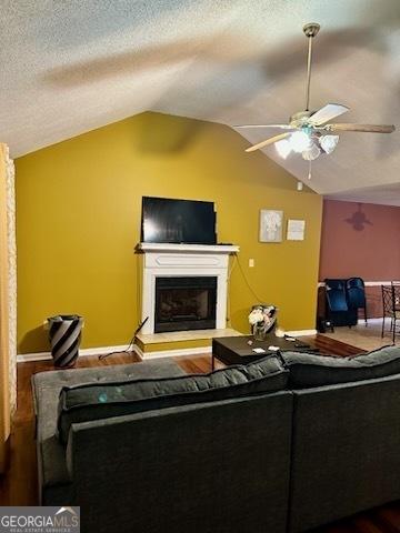 living room with hardwood / wood-style flooring, ceiling fan, lofted ceiling, and a textured ceiling