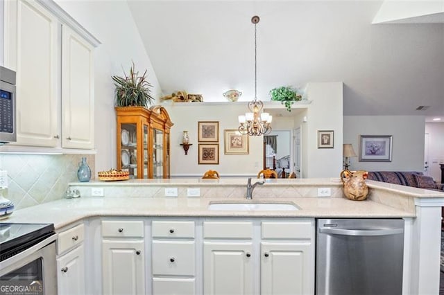 kitchen with pendant lighting, white cabinets, sink, appliances with stainless steel finishes, and kitchen peninsula