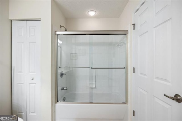 bathroom with enclosed tub / shower combo and a textured ceiling