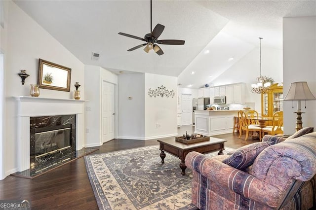 living room featuring dark hardwood / wood-style flooring, high vaulted ceiling, a textured ceiling, a fireplace, and ceiling fan with notable chandelier