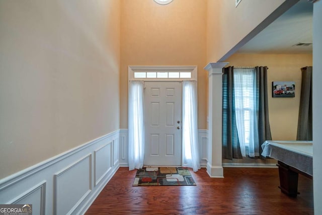 entrance foyer featuring dark wood-type flooring and decorative columns