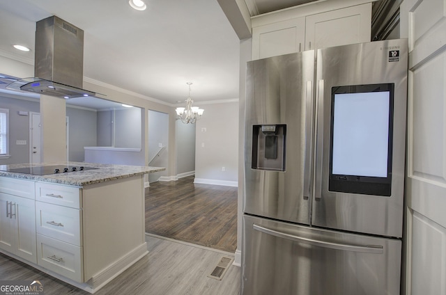 kitchen with stainless steel fridge, black electric cooktop, light stone counters, white cabinetry, and island exhaust hood