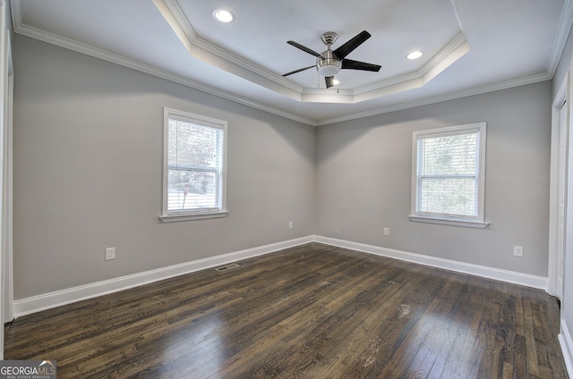 spare room with dark wood-type flooring, a tray ceiling, ceiling fan, and ornamental molding