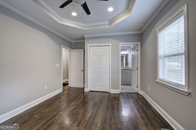 unfurnished bedroom with ceiling fan, multiple windows, connected bathroom, and a tray ceiling