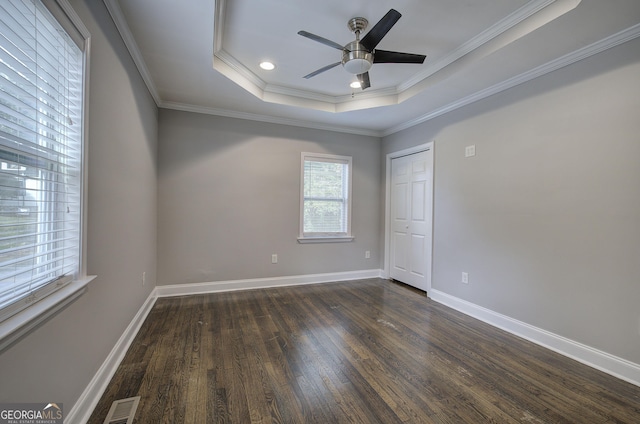 spare room featuring dark wood-type flooring, a raised ceiling, ceiling fan, and ornamental molding