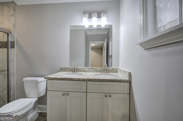 bathroom with vanity, toilet, a shower with shower door, and crown molding